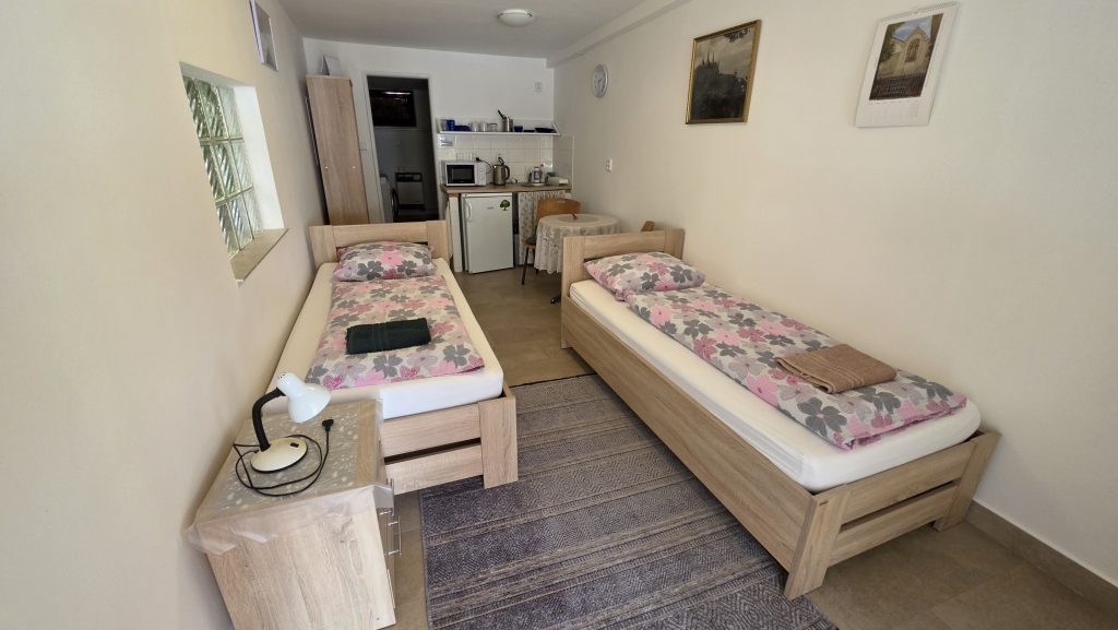 Pokoj v přízemí se dvěma lůžky a kuchyňkou v pozadí