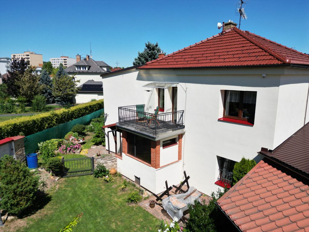 Pension z boku — balkon s posezením a kvetoucí zahrada