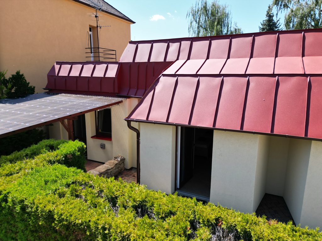 Červená střecha přístavby a vstup do apartmánů v přízemí